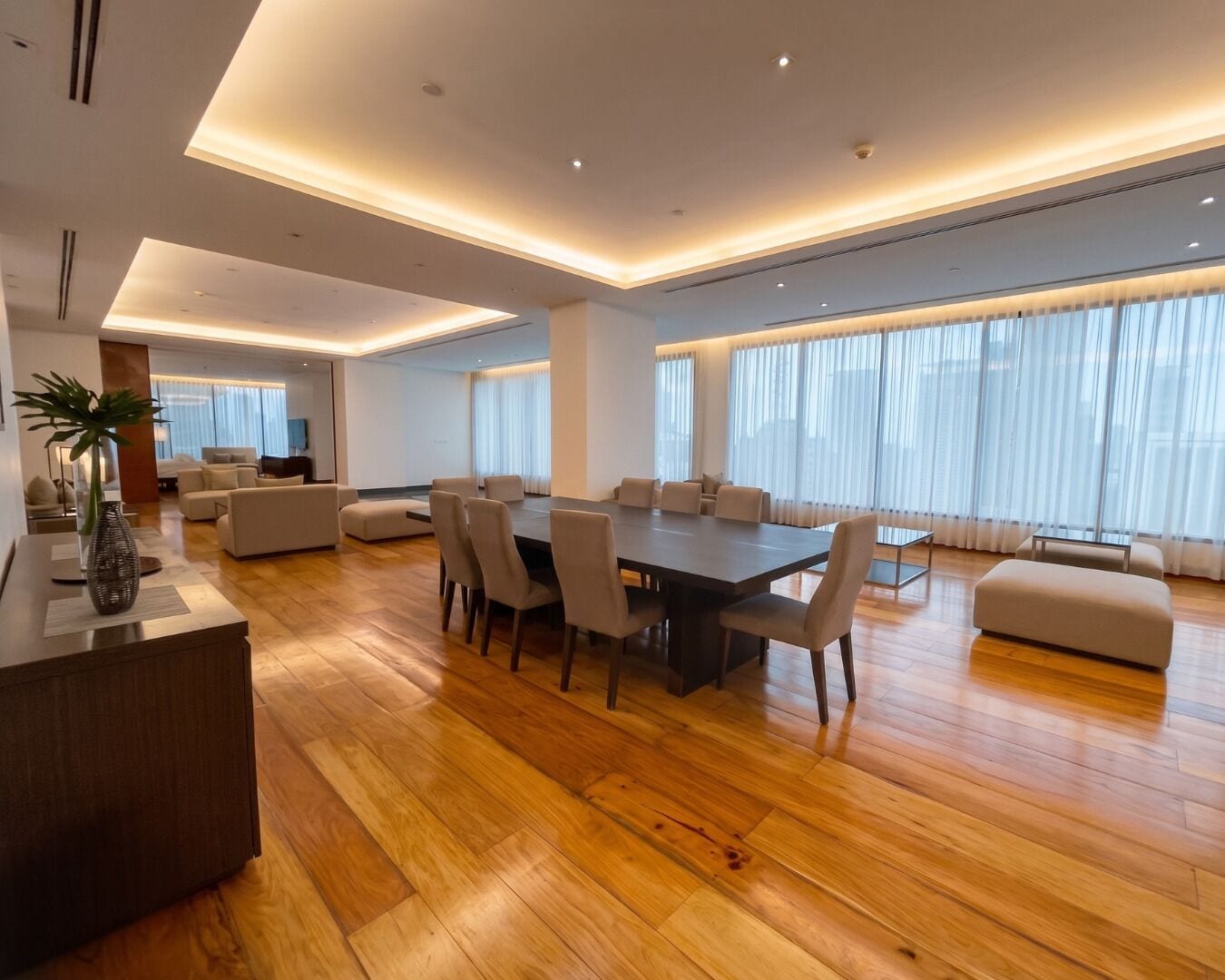 A spacious living area with a large dining table, comfortable seating, and a modern design.