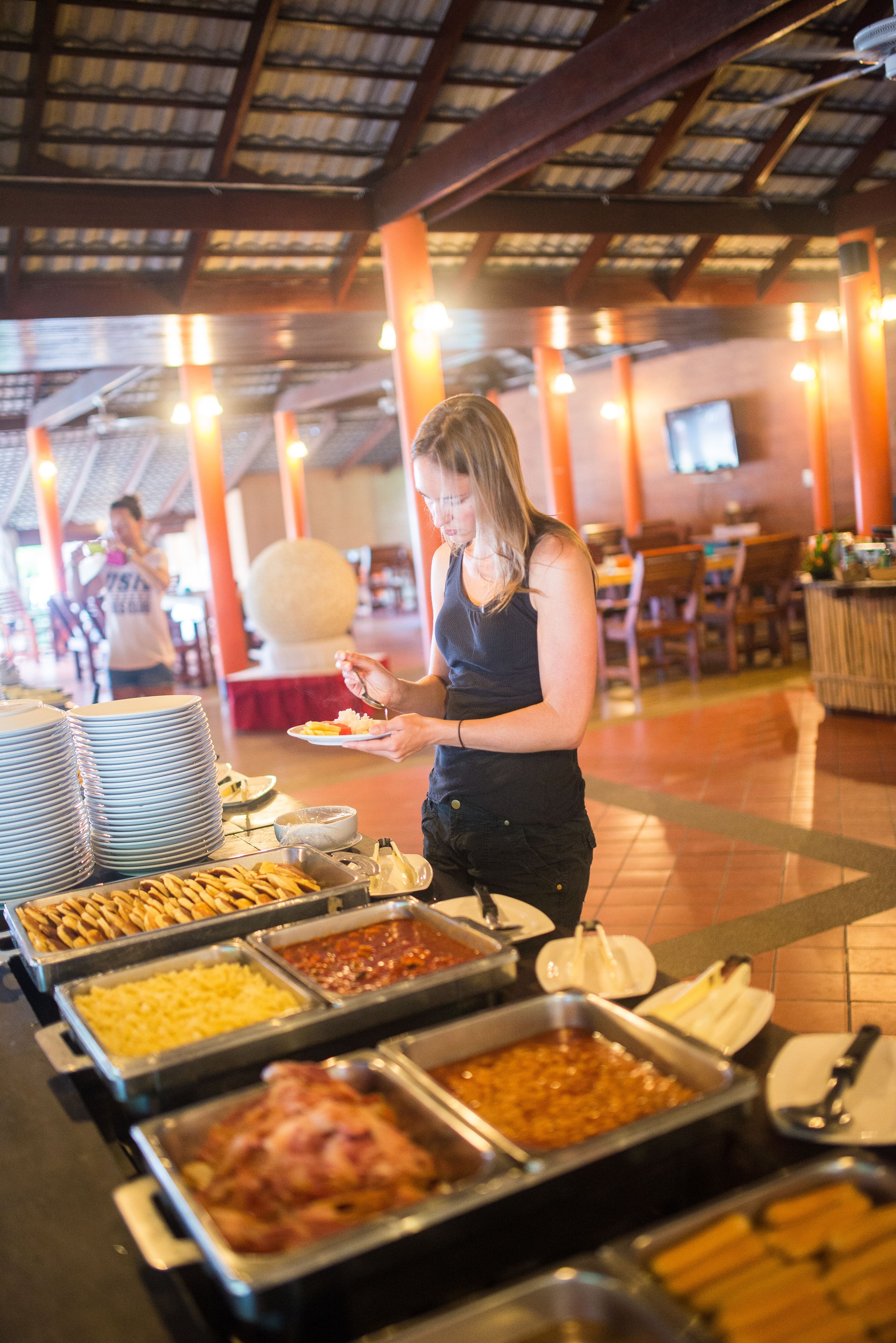 A buffet area with various food options and a person serving themselves.