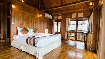 A wooden room with a large bed, wooden walls, and a window.