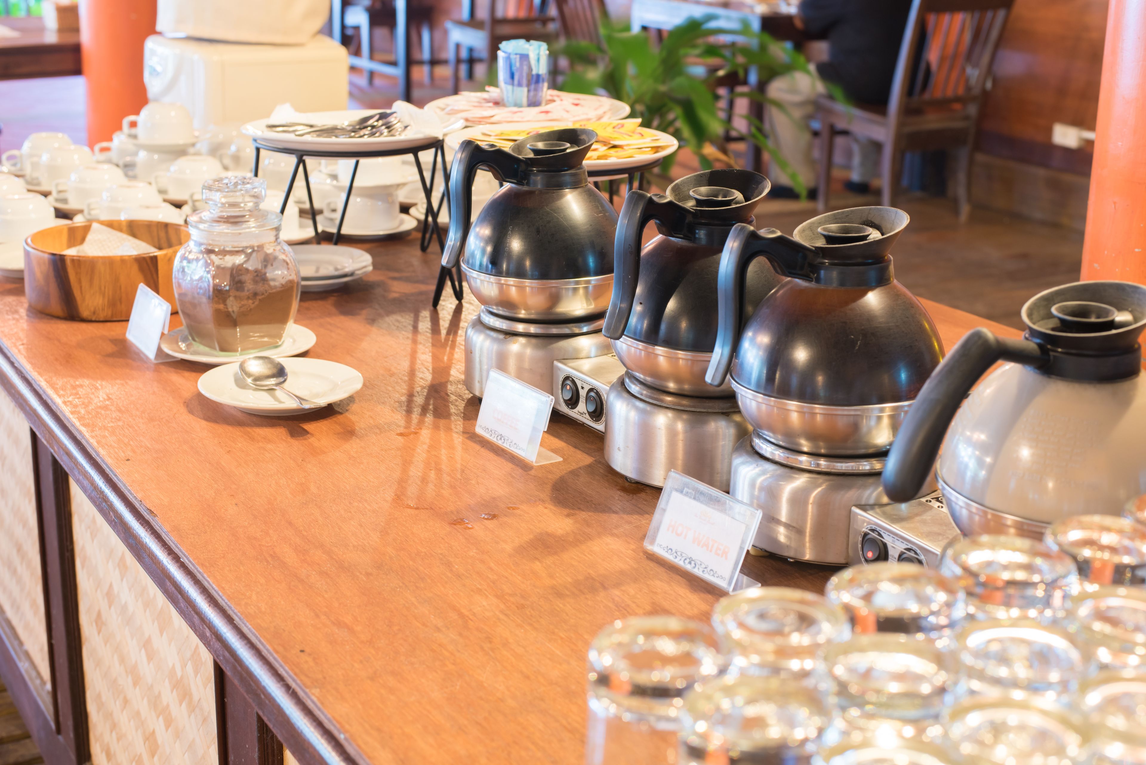 Eine Kaffeestation mit verschiedenen Kaffeemaschinen und einer Auswahl an Tassen und Untertassen.