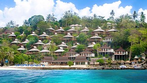 Un complexe hôtelier doté de plusieurs bungalows sur pilotis, d’une plage et d’une végétation luxuriante.