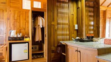 Interior de una cabaña de madera con kitchenette, piso de madera y techo con vigas a la vista.