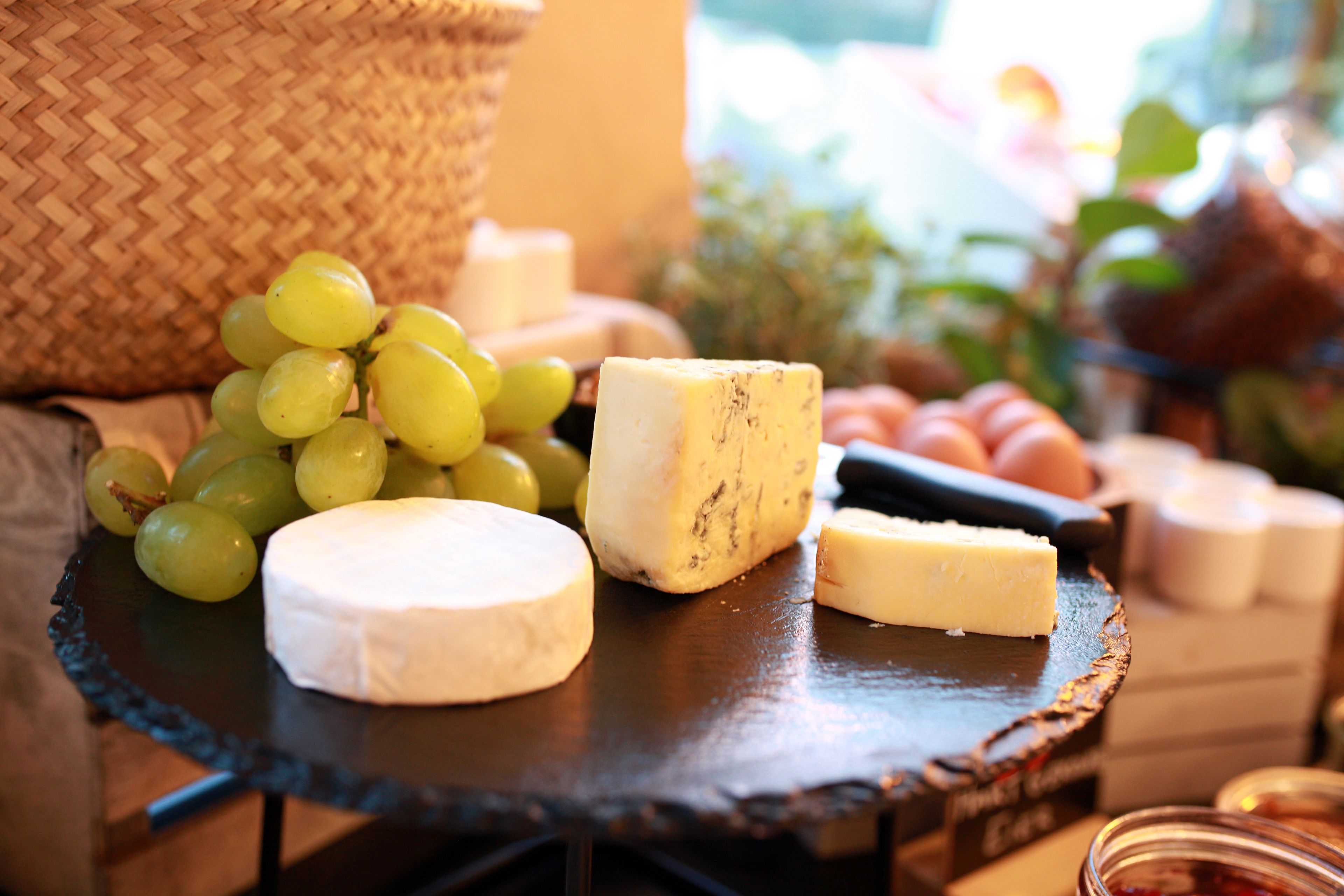 A cheese board with various cheeses and grapes.
