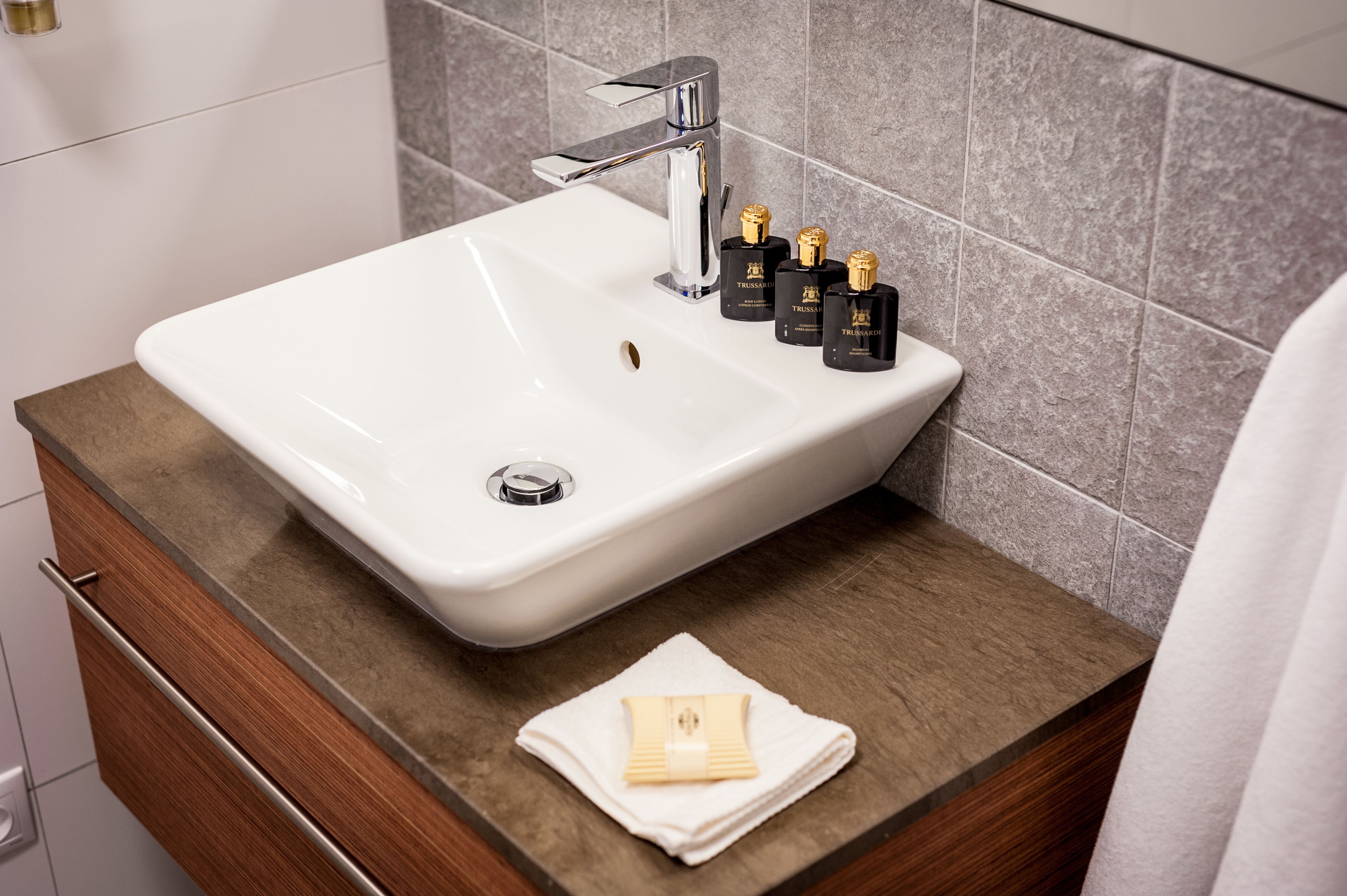 Ein Badezimmer mit einem weißen Waschbecken, einem Holz-Waschtisch und einem Handtuch.
