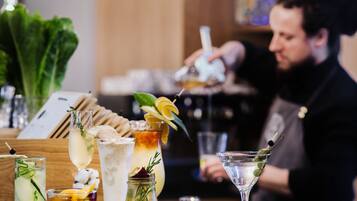 Eine Bar mit verschiedenen Getränken, einem Barkeeper und hängenden Lichtern.