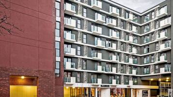 A multi-story hotel with a modern design, featuring balconies, large windows, and a brick facade.