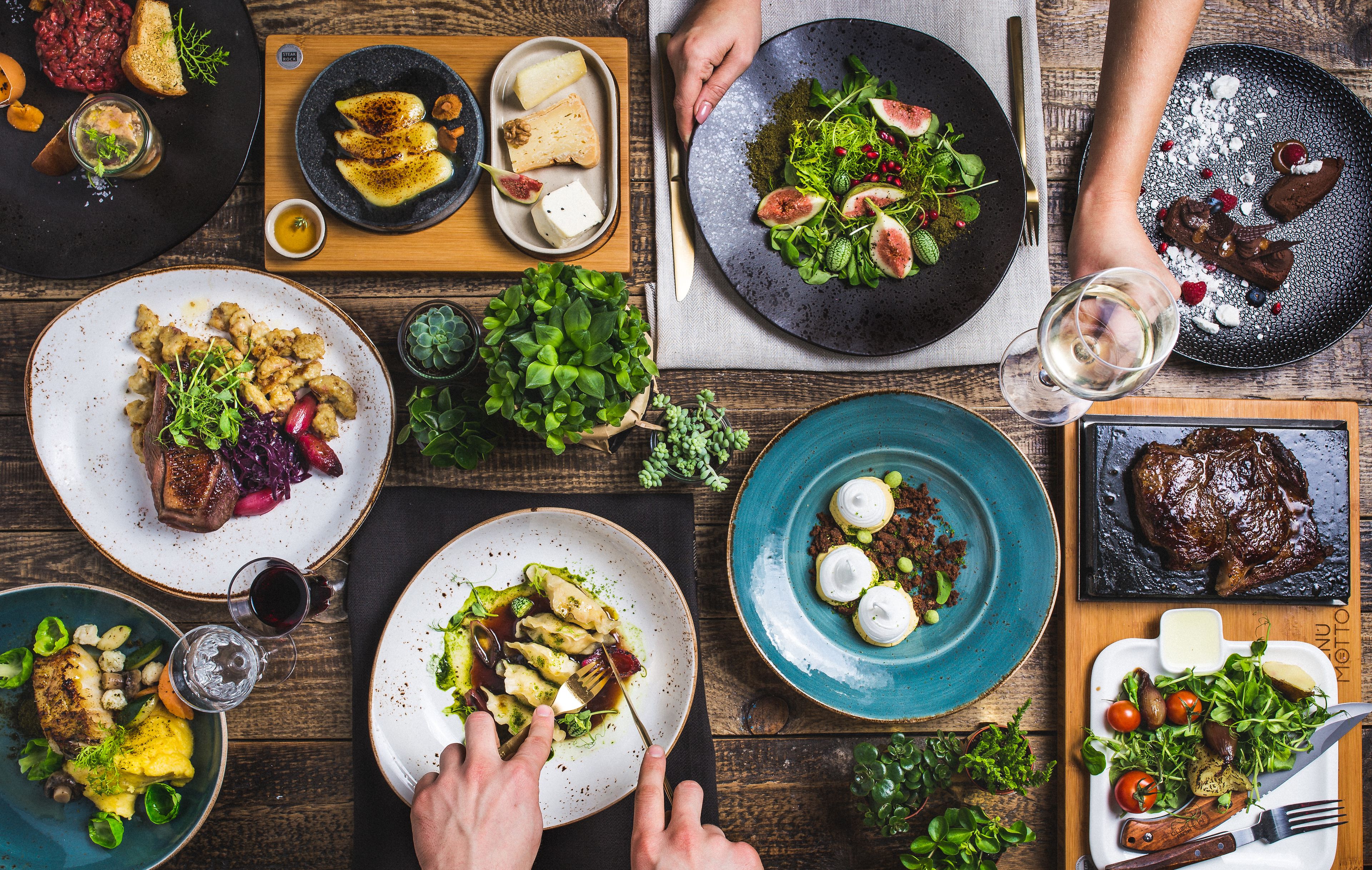 A dining table with various dishes, including steak, pasta, and salads, suggesting a restaurant setting.