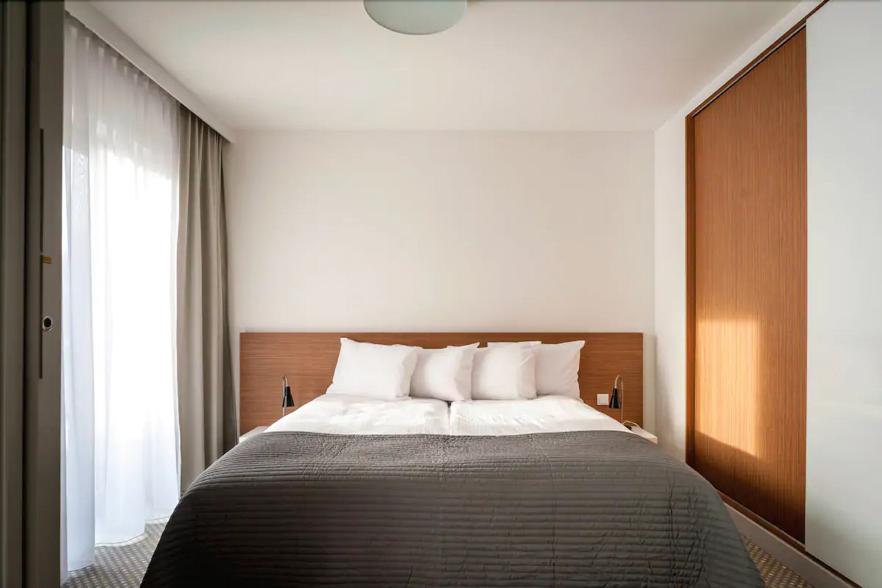 A hotel room with a large bed, a wooden headboard, and a wardrobe.