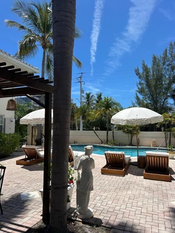 Una piscina al aire libre, sombrillas, tumbonas