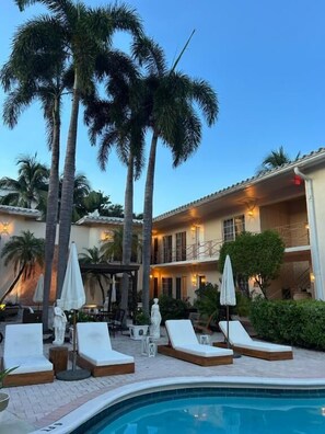 A poolside area with lounge chairs, umbrellas, and a building with multiple balconies. - La Casa A North Beach Village Resort Hotel (Fort Lauderdale)