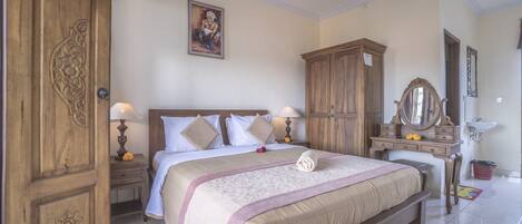 A bedroom with a large bed, wooden wardrobe, bedside tables, a mirror, and a painting on the wall.