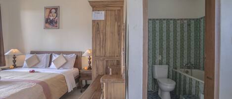 Une chambre d’hôtel avec un lit, une table de chevet, une lampe et une armoire en bois.