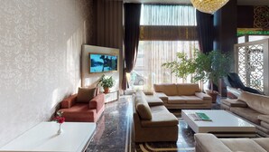 Un amplio salón con un conjunto de sofá, una mesa de centro y un televisor montado en la pared.