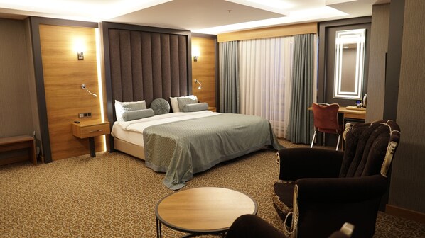 A hotel room with a large bed, a desk, a chair, and a small table. - Green Prusa Hotel (Bursa)
