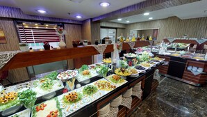 Un bufé con diversos alimentos y una ventana decorativa con cortinas.