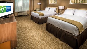 Habitación de hotel con dos camas, un escritorio con televisor, una ventana con cortinas y una obra de arte colgada en la pared.