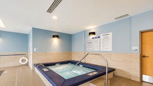 Zona de spa con una bañera de hidromasaje, un cartel de precaución y una señal de equipo de piscina.