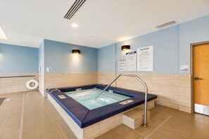 Un espace bien-être comprenant un jacuzzi, un panneau d’avertissement et un panneau indiquant les règles d’utilisation de la piscine.