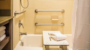 A bathroom with a bathtub, a shower, and a handrail for accessibility.