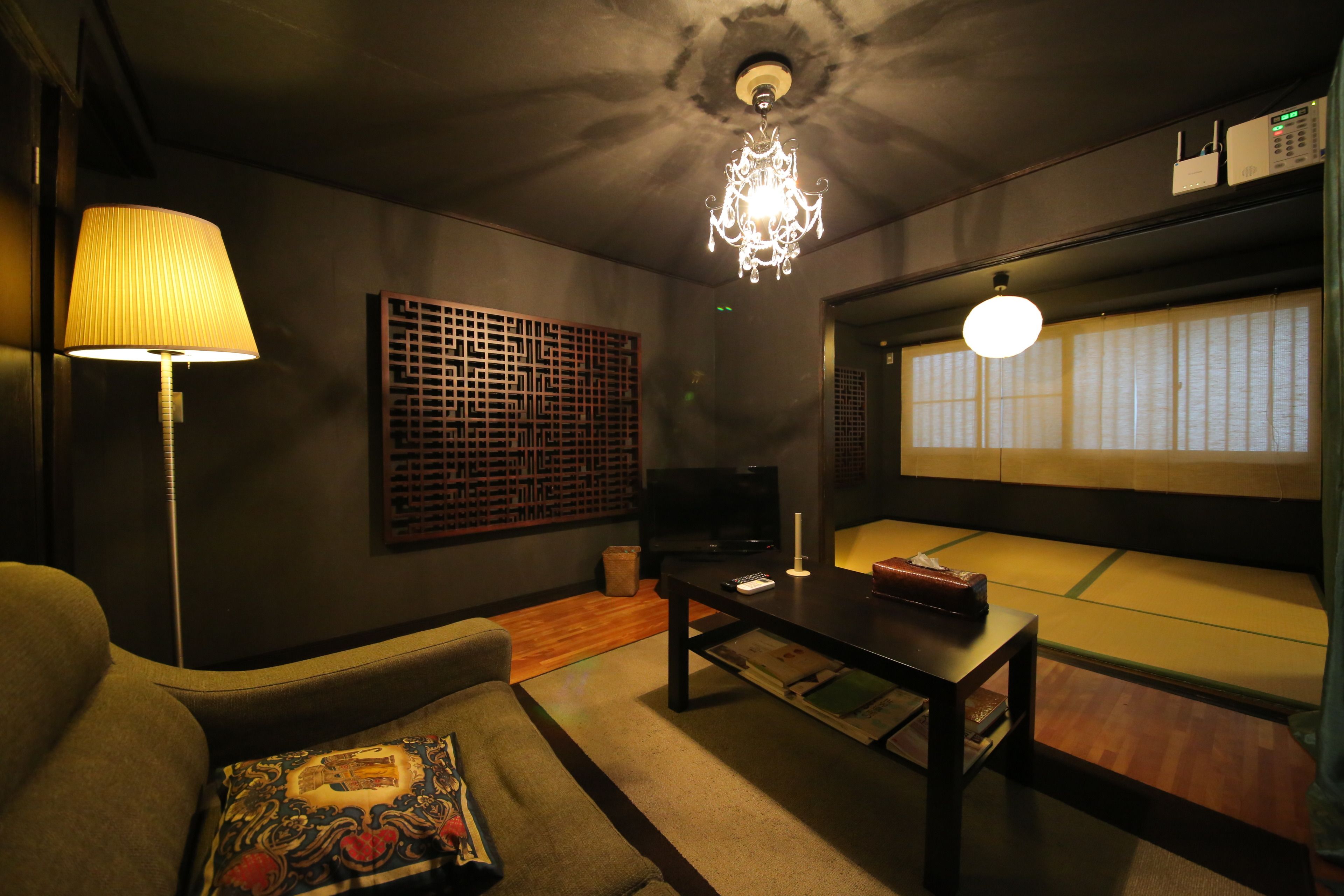 A living room with a sofa, a coffee table, a lamp, a TV, and a traditional Japanese sliding door.