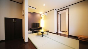 A room with tatami flooring, a television, a small table, and a sofa.