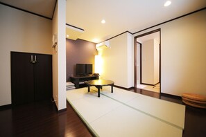 Relax in a serene space with a tatami mat floor, flat-screen TV, and cozy table with a lamp.