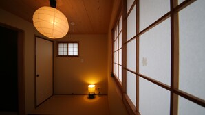 A traditional Japanese room with tatami flooring, a shoji screen door, and a hanging paper lantern.