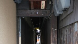 A narrow alleyway with a wooden door on the right and a concrete path leading forward.