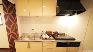A compact kitchen with a sink, a stove, and a dishwasher. There are cabinets and a countertop with various items on it.