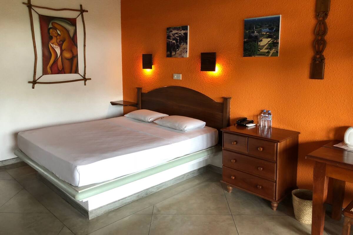 A neatly arranged bedroom with a bed, bedside table, and a small desk.