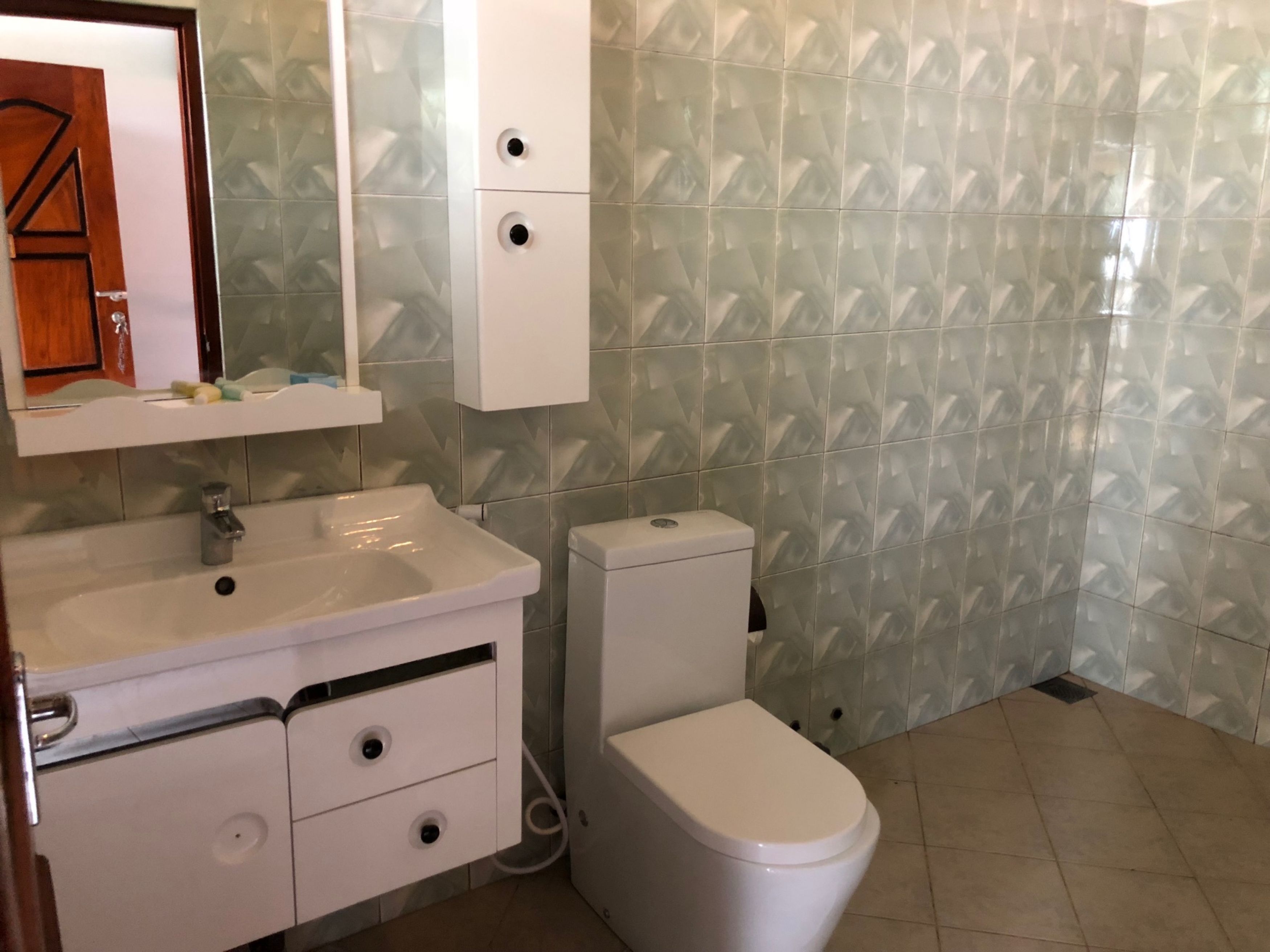 Un baño con un lavamanos blanco, un inodoro y un espejo sobre el lavamanos.