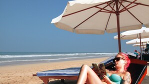 A beach scene with a woman lying on a sun lounger under a beach umbrella, reading a book. - Wunderbar Beach Hotel (Bentota)