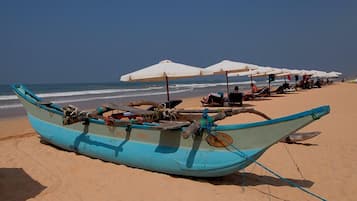 Een privéstrand, wit zand, ligstoelen aan het strand, parasols