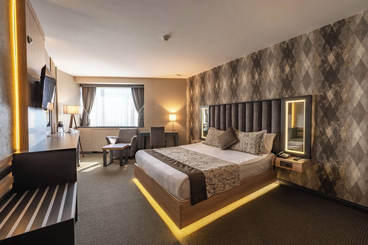 Habitació d'hotel moderna amb un llit gran, taules de nit, escriptori i una cadira.