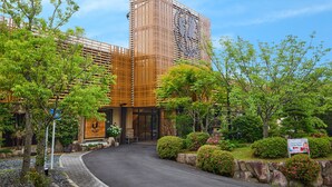 Un edificio moderno con una entrada curva, rodeado de jardines cuidados y árboles.