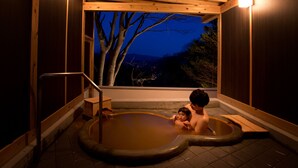 Un baño de aguas termales de madera con vistas a árboles y montañas.