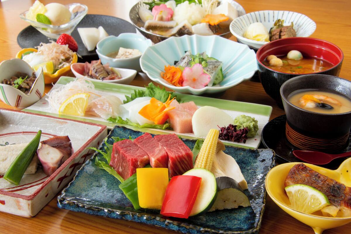 A variety of dishes including sashimi, vegetables, and a bowl of soup.