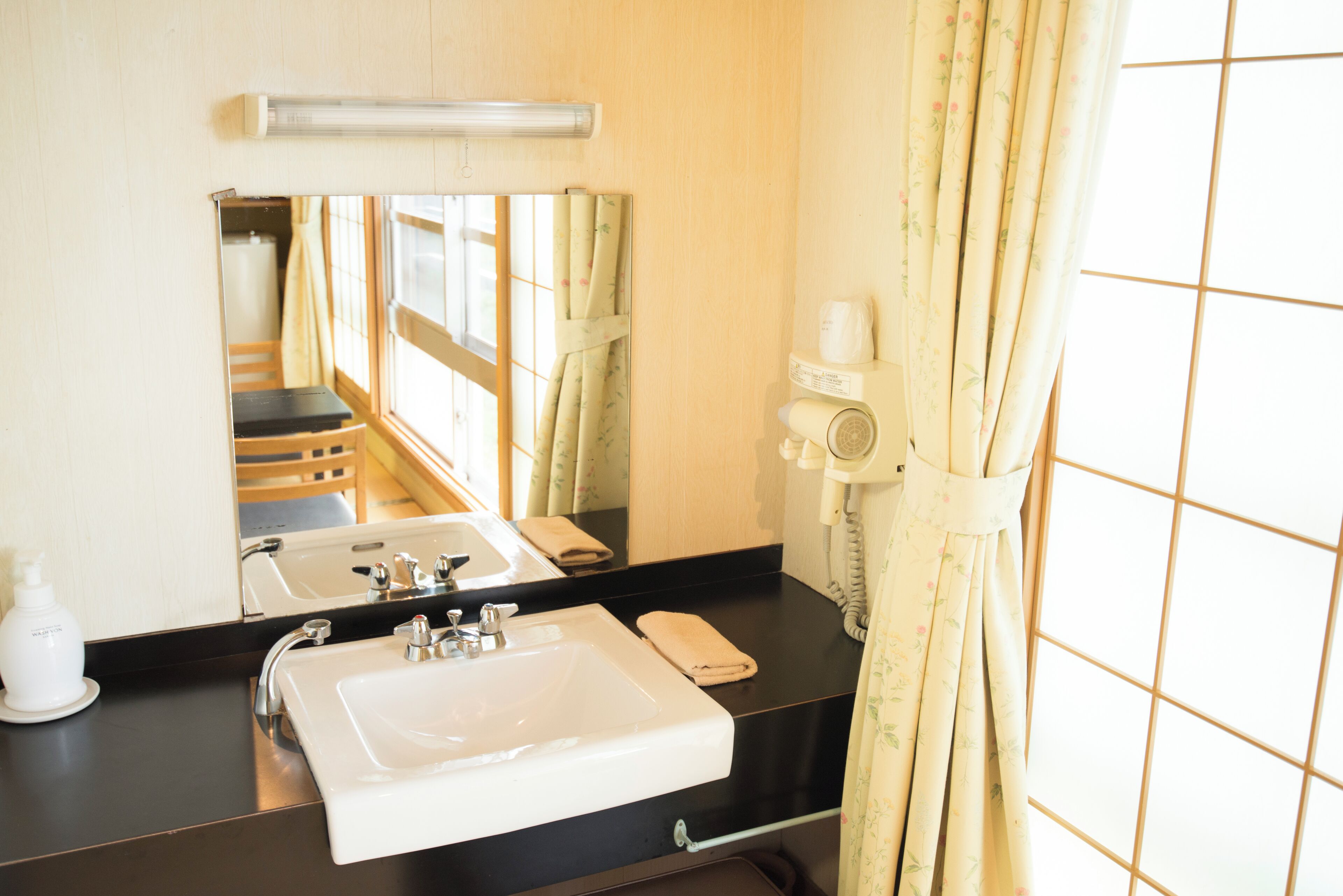 A hotel bathroom with a sink, mirror, and a hairdryer on the counter.
