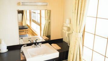 A hotel bathroom with a sink, mirror, and a hairdryer on the counter.