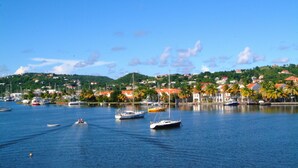 A marina with several boats, a clear blue sky, and a hillside with houses. - Cleopatra Villas (Gros Islet)