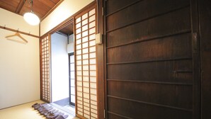 A traditional Japanese room with tatami flooring, a sliding door, and a hanging light fixture.