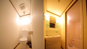 A compact bathroom with a toilet, sink, and shower.
