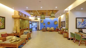 A spacious lobby with a wooden ceiling, a reception desk, comfortable seating areas, and decorative wall art. - MAYFAIR Waves (Puri)
