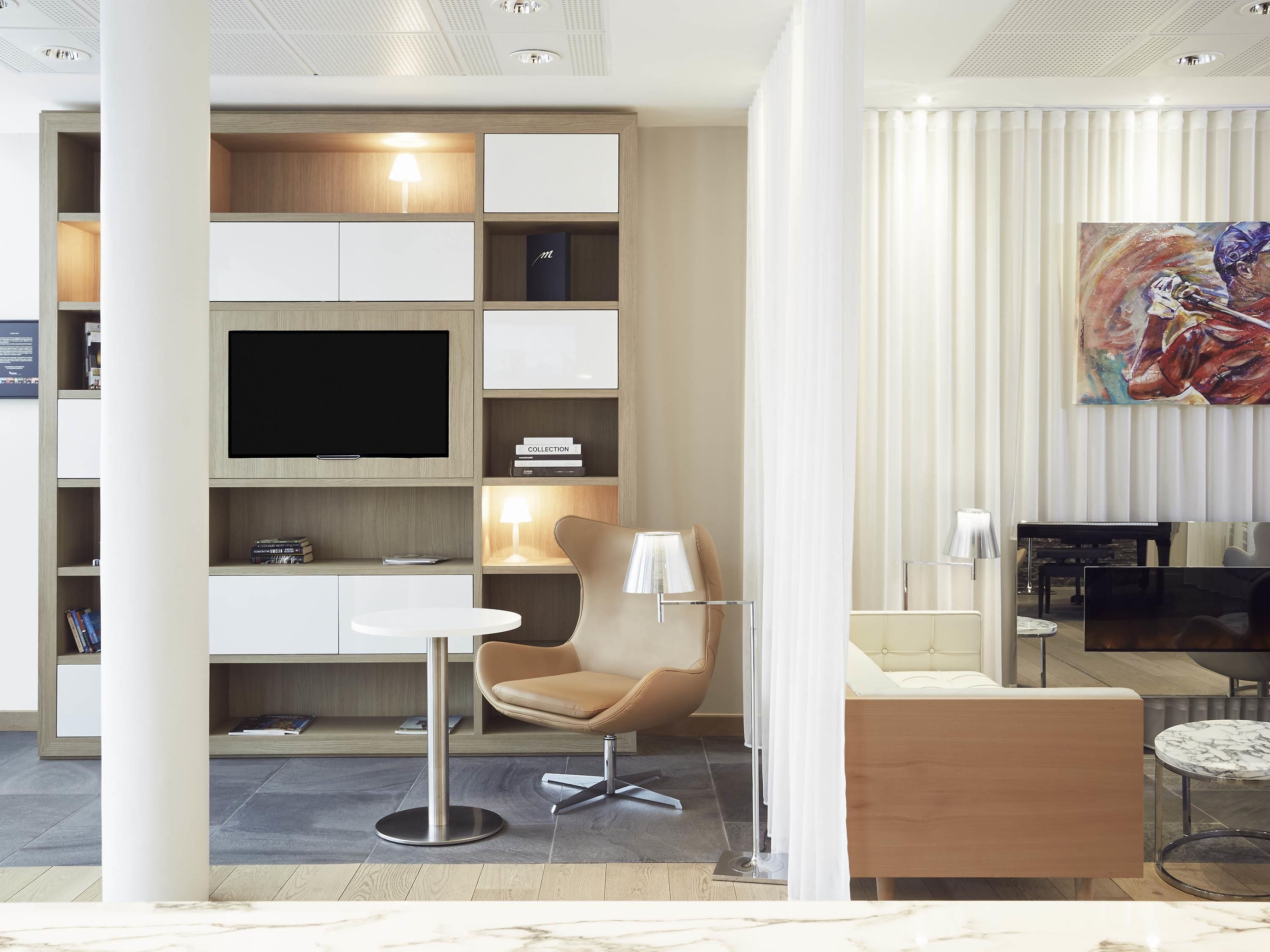 A modern living room with a flat-screen TV, a sofa, a chair, and a coffee table.