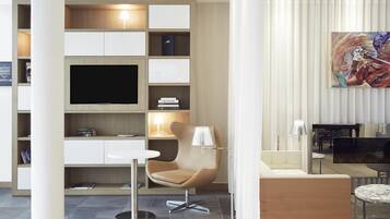 A modern living room with a flat-screen TV, a sofa, a chair, and a coffee table.