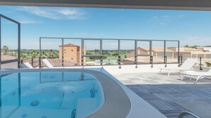 A rooftop pool area with a hot tub, lounge chairs, and a view of surrounding buildings and greenery. - Mercure Golf Cap d'Agde (Agde)