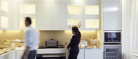 A modern kitchen with white cabinetry, a built-in oven, and a coffee machine.