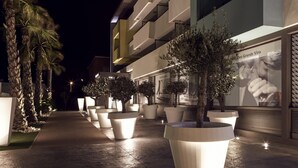A modern building with a well-lit outdoor area featuring large planters and palm trees. - Mercure Golf Cap d'Agde (Agde)