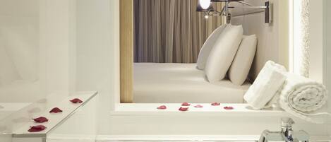 Une salle de bain moderne avec une baignoire, un miroir et un luminaire fixé au mur.