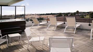 Terraza en la azotea con sillones de descanso, bañera de hidromasaje y vistas de la ciudad.